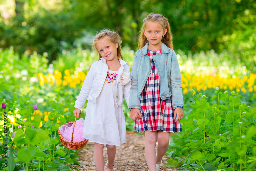 Fototapeta premium Little adorable girls walking in spring garden outdoors