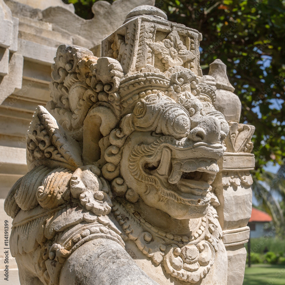 Traditional guard demon statue carved in dark stone on Bali island, Indonesia