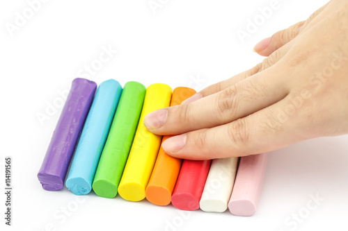 Hand pressing colorful rod plasticine arranging on white backgro