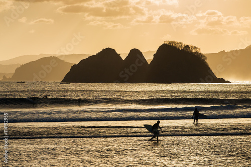Canvas Print Silhouette of surfers walking in the beach at sunset