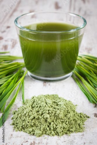 Heap of young powder barley, barley grass and beverage on old wooden background