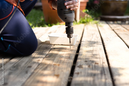 Carpenter using drill on wooden floor photo