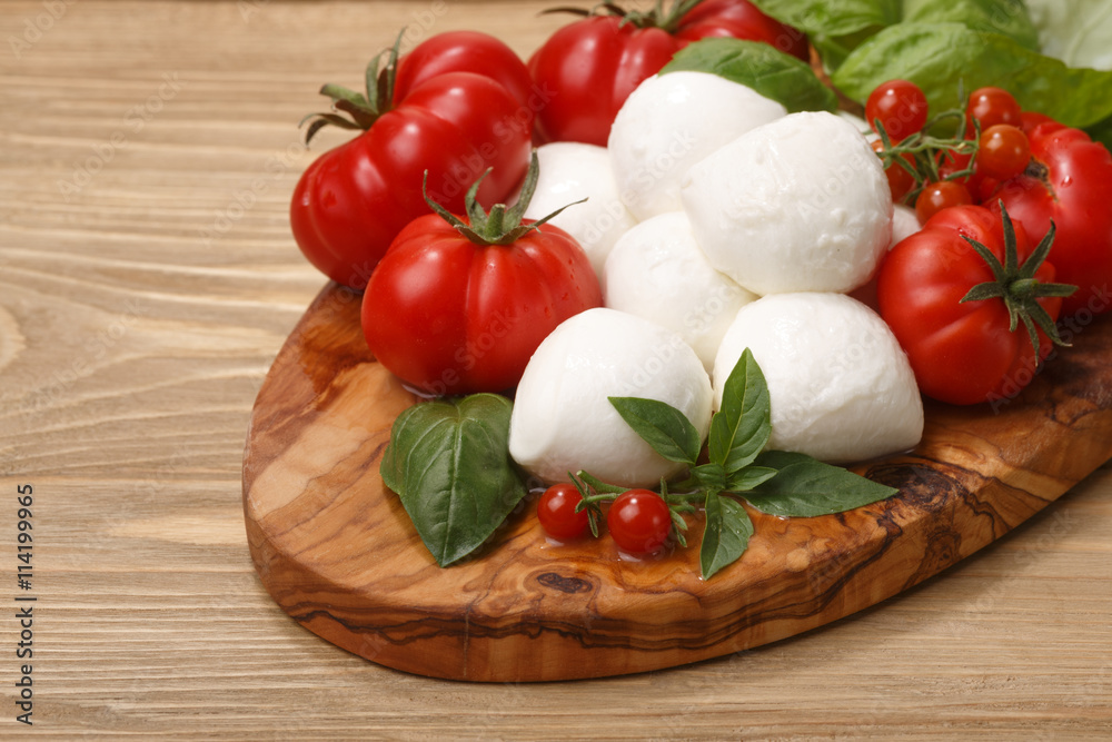 Mozzarella, heirloom tomatoes, basil leaves on a wooden serving