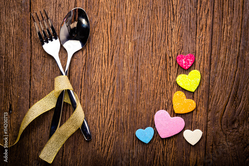 Couple love concepe. Fork and spoon with love hearts on wooden background photo