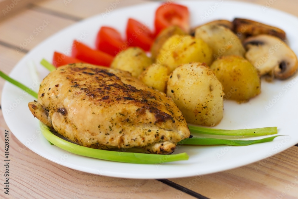 fried chicken fillet with potatoes tomatoes and mushrooms. on a wooden background fried chicken fillet with potatoes tomatoes and mushrooms. on a wooden background