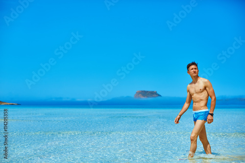 man standing in the sea on the beach. man wearing in blue swimming trunks