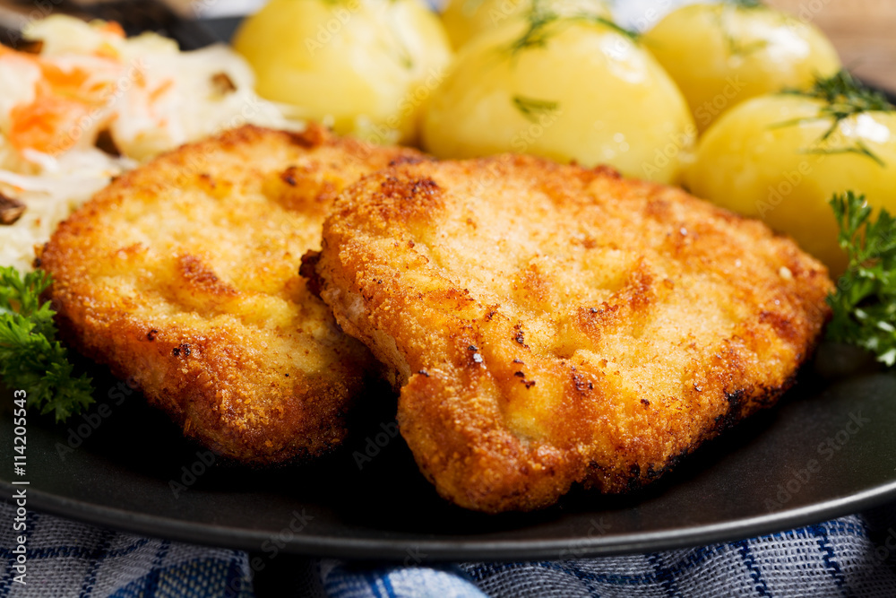 Fried pork chop in breadcrumbs, served with boiled potatoes and Fried pork chop in breadcrumbs, served with boiled potatoes and