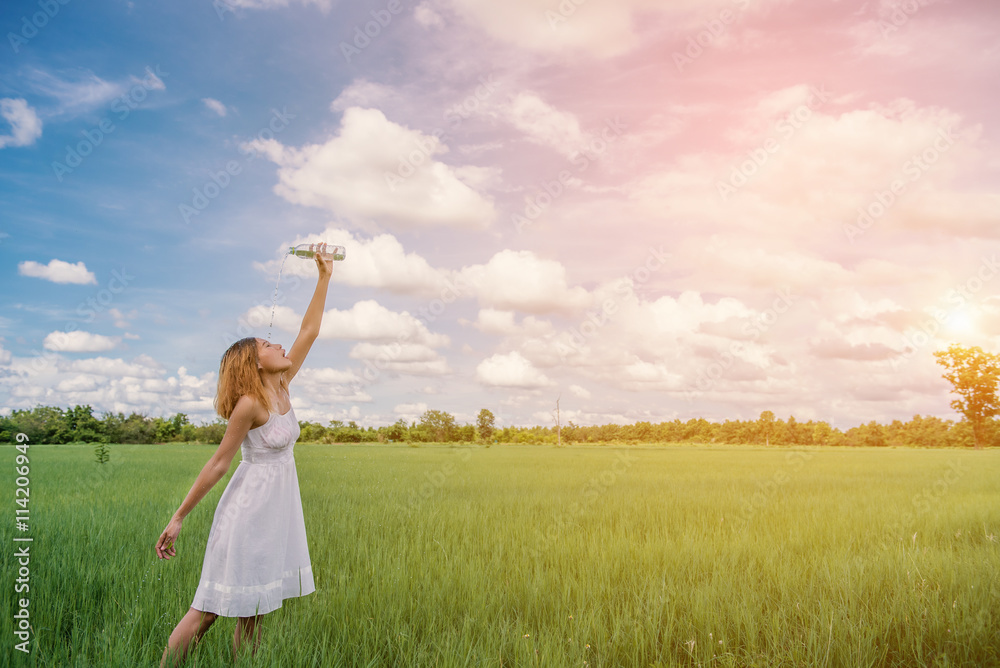 Woman drinking water on green meadow background.blue sky. Woman drinking water on green meadow background.blue sky.
