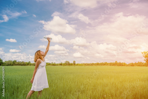 Woman drinking water on green meadow background.blue sky.