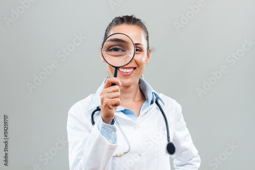 Portrait of beautiful female doctor looking through loupe.