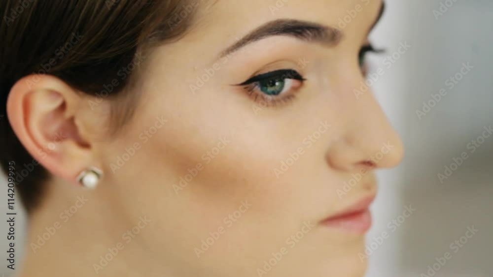 Beautiful fashion model girl whose makeup artist apply highlighter, close-up Beautiful fashion model girl whose makeup artist apply highlighter, close-up