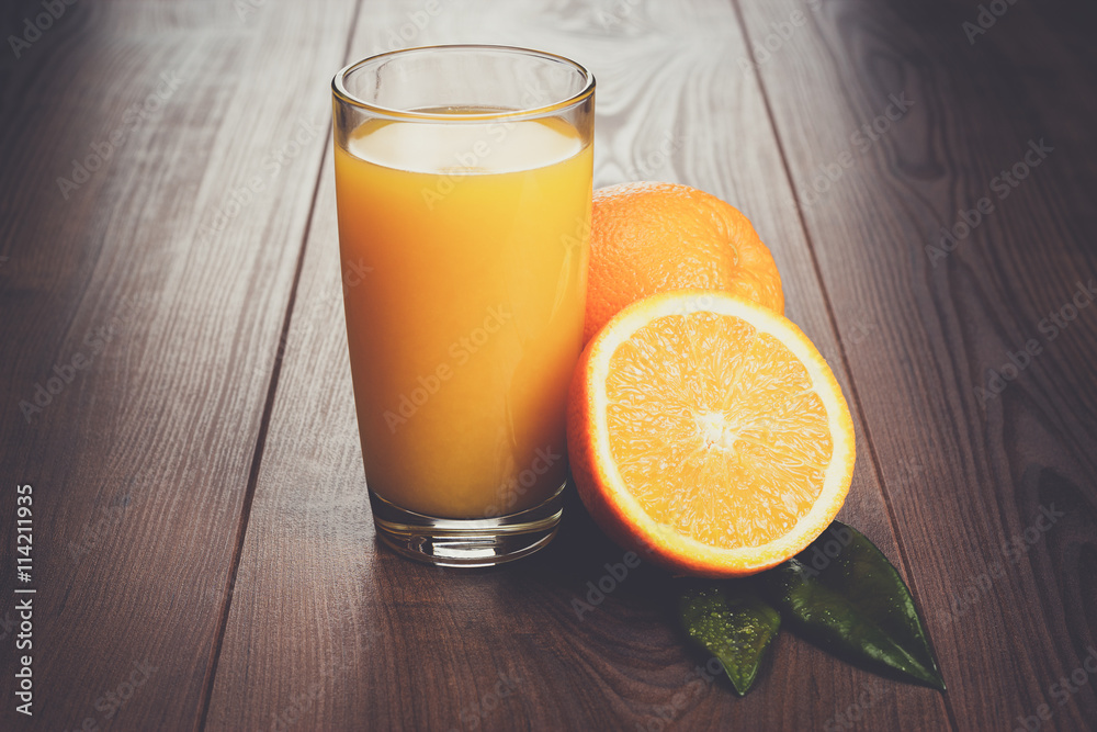 fresh orange and glass with juice on the brown wooden table fresh orange and glass with juice on the brown wooden table