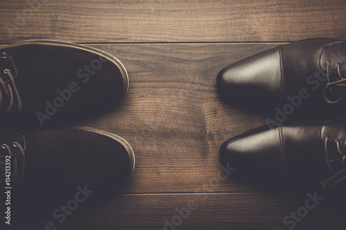 two pairs of brown shoes on the wooden table