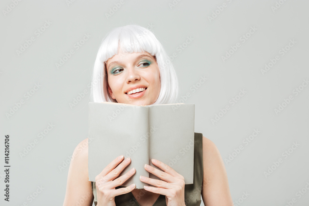 Happy woman in blonde wig smiling and reading a book Happy woman in blonde wig smiling and reading a book