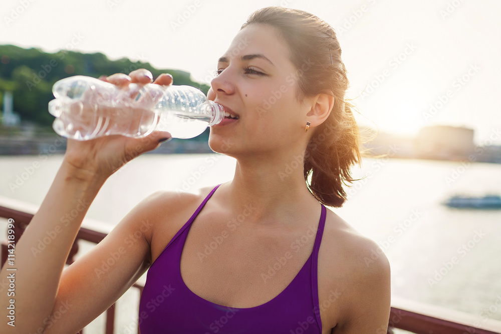 attractive young woman taking a water break while out on a run attractive young woman taking a water break while out on a run