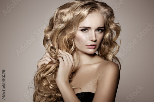 Model with blonde long hair. Waves Curls Hairstyle. Hair Salon.
