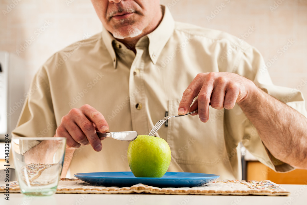 Fototapeta premium Obscured man slicing apple over blue plate