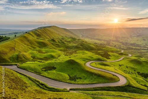 Obraz Długa kręta wiejska droga prowadząca przez wiejską okolicę w English Peak District z pięknym wieczornym światłem słonecznym.
