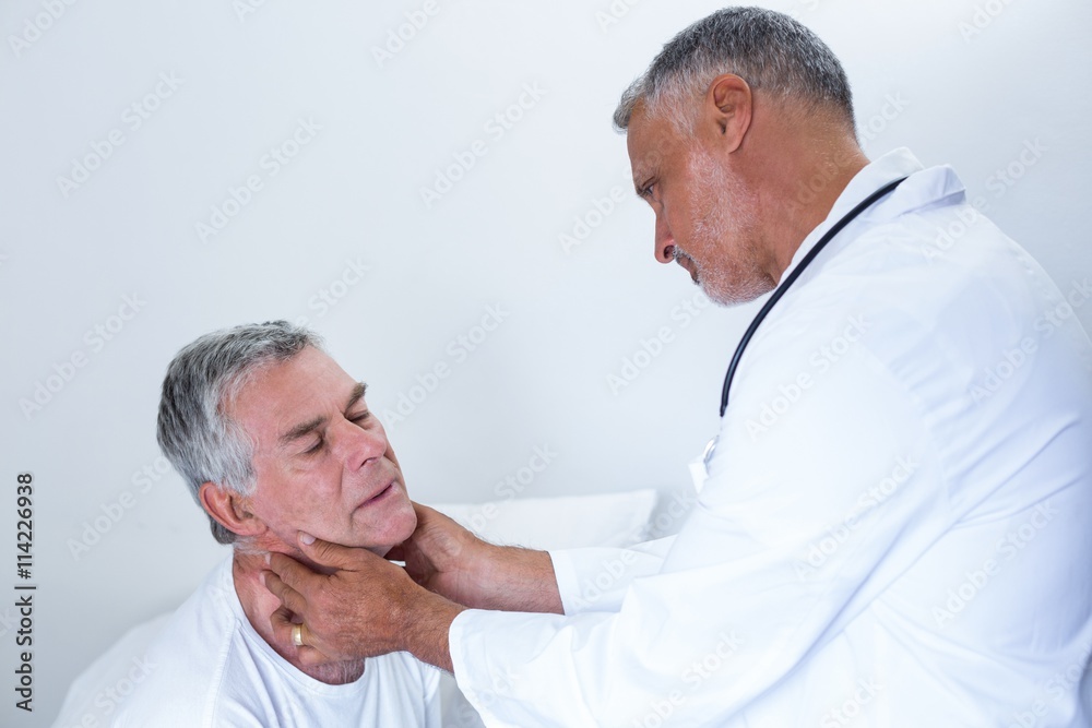 Fototapeta premium Male doctor examining senior mans neck