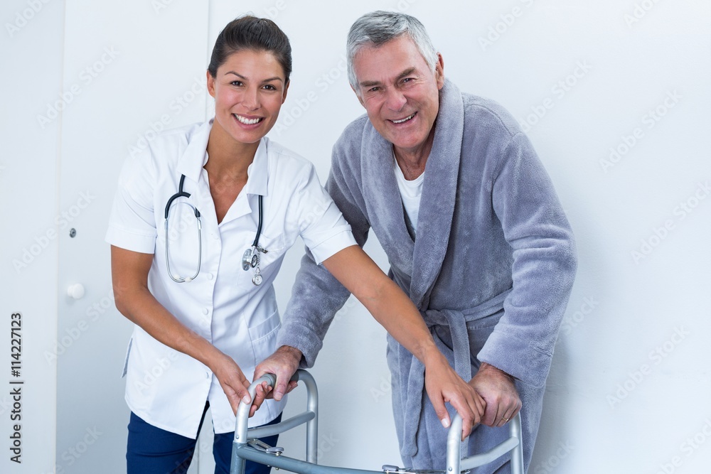 Obraz premium Portrait of female doctor helping senior man to walk with walker