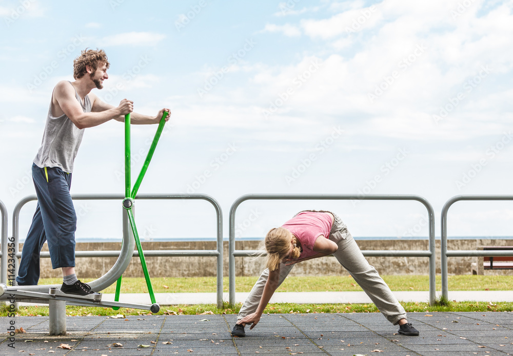 Fototapeta premium Man exercising on elliptical trainer and woman.