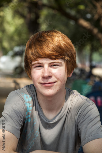 boy with red hair and pickax in the face looks happy and keepts the arms crossed
