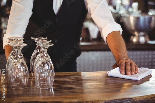 Mid section of bartender cleaning a bar counter
