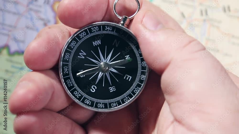 Hand holding a compass with swinging needle looking for North Hand holding a compass with swinging needle looking for North