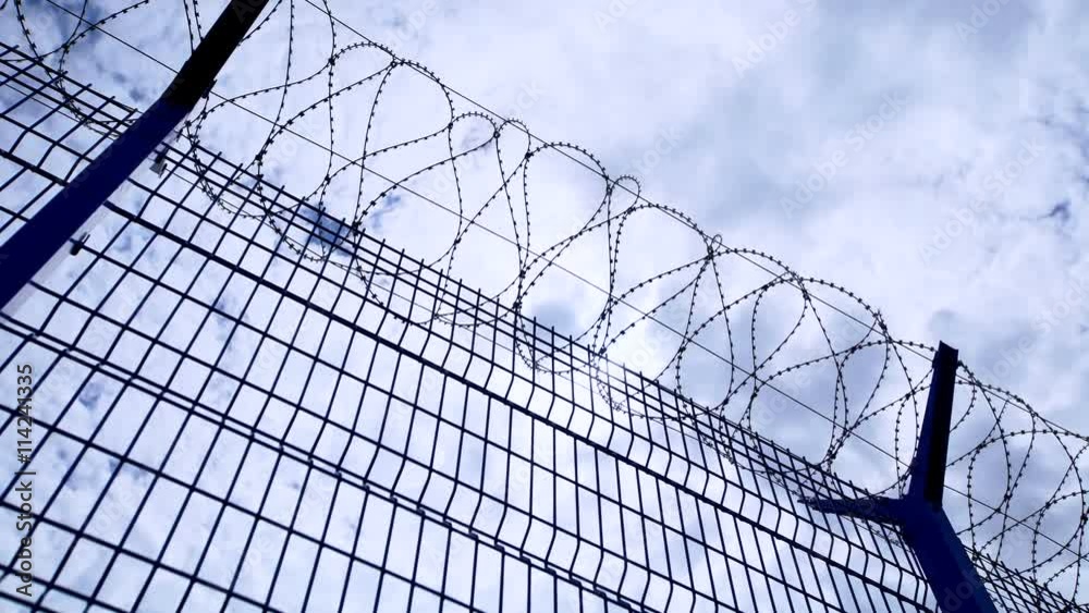 Timelapse of clouds and blue sky over barbed wire