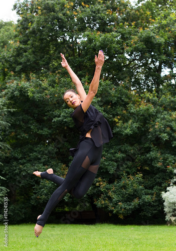 A jazz dancer performing a jump outdoors