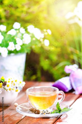 Fototapeta Naklejka Na Ścianę i Meble -  Cup of tea on a wooden backgound. Flowers and grass. Natural background. Agricultural.Garden