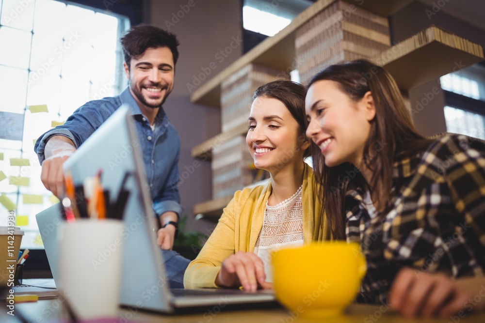 Fototapeta premium Coworkers smiling while discussing over laptop 