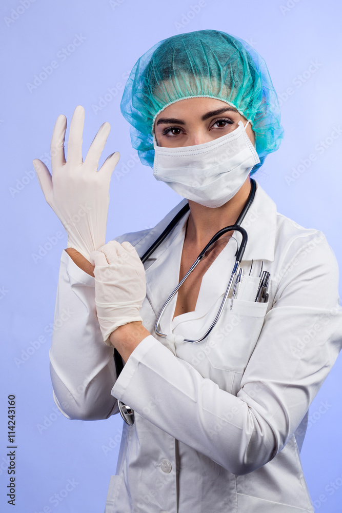 Medico donna con guanti, camice mascherina e cuffietta verde si sistema  unguento prima di operare - isolata su sfondo chiaro Stock Photo | Adobe  Stock