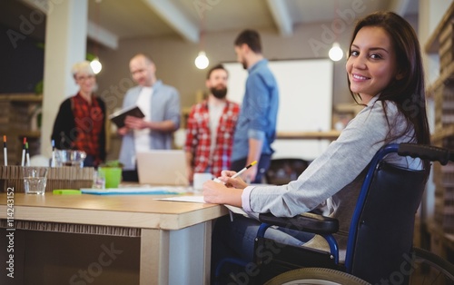 Confident disabled businesswoman writing at desk 