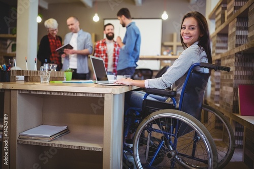 Fotografi Confident disabled businesswoman using laptop in office