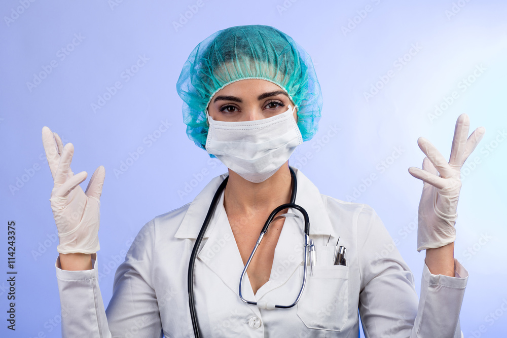 Medico donna con guanti, camice mascherina e cuffietta verde è pronto a curare o operare - isolata su sfondo chiaro Medico donna con guanti, camice mascherina e cuffietta verde è pronto a curare o operare - isolata su sfondo chiaro