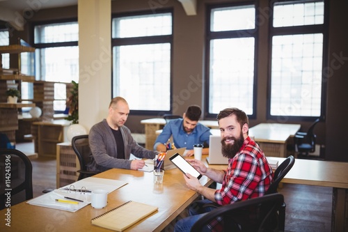 Businessman using tablet while colleagues working in office