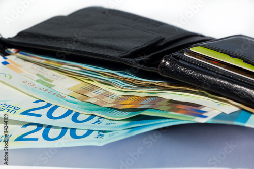 Stack of various of israeli shekel money bills in open black leather wallet