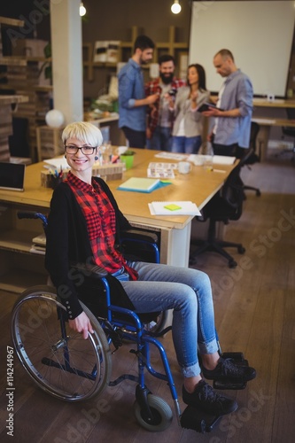 Portrait of young disabled businesswoman by desk