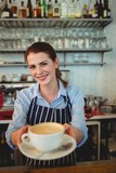 Portrait of confident barista serving coffee at cafeteria