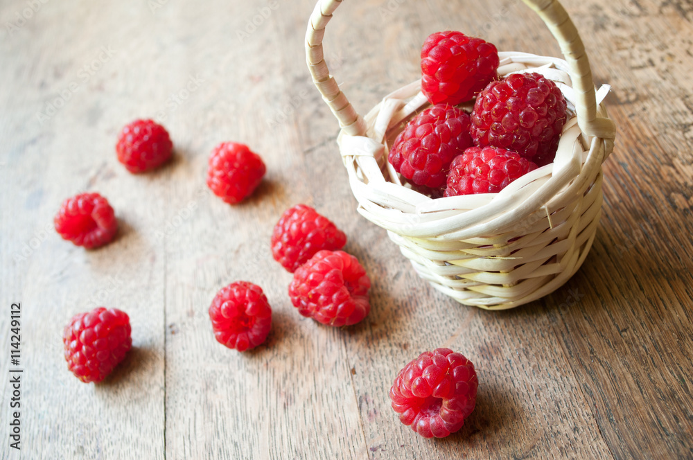 framboises et petit panier en osier sur table en vieux bois framboises et petit panier en osier sur table en vieux bois