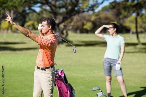 Golfer pointing while standing by woman 