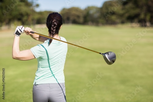 Rear view of golfer woman taking shot
