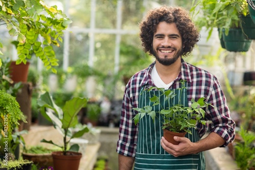 Smiling male gardener holding potted plant