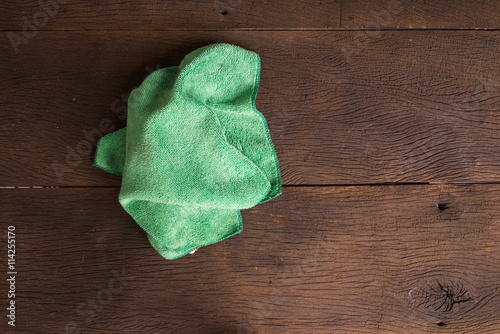 Green cleaning rag on wood background