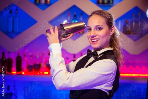 Barmaid with cocktail shaker at counter