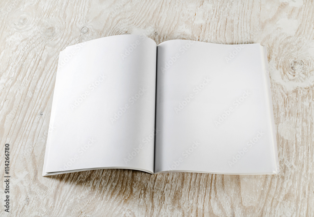Fototapeta premium Blank opened book with soft shadows on light wooden background. Responsive design template. Mock-up for your design. Top view.