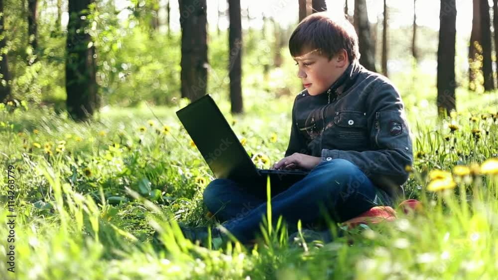 Teen boy child with a PC laptop, communicate via Internet by notebook outdoor Teen boy child with a PC laptop, communicate via Internet by notebook outdoor