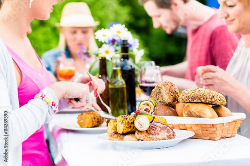 Freunde essen Grillwürste und Fleisch auf Garten- oder Grillfest