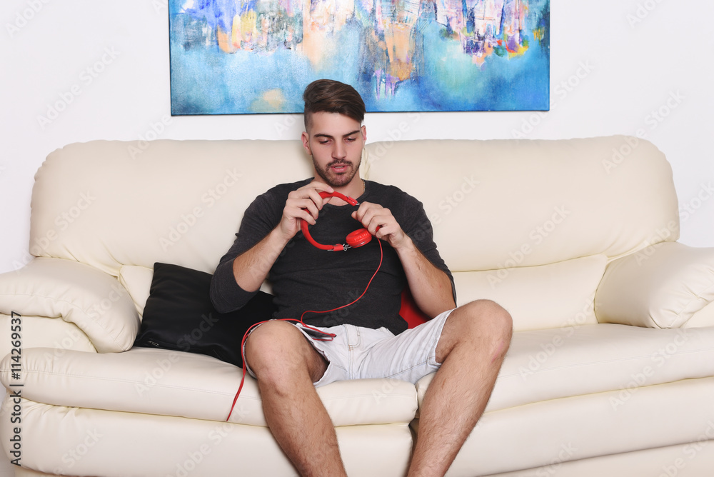 Young man relaxing on white sofa with headphones.